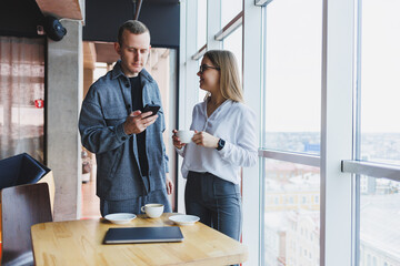 Smart young professionals in casual clothes checking data on the phone and taking notes while...