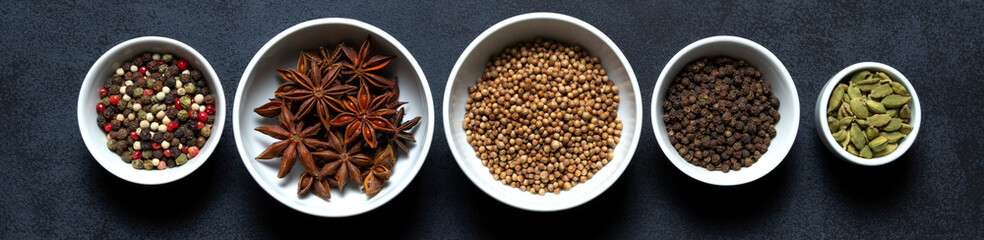 Spices assorted multicolor peppercorns, cardamom, star anise, cumin, coriander, caraway in bowls on...