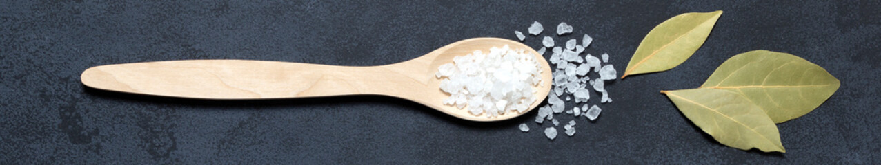 Banner spices and herbs bay leaf and salt in wooden spoon on black background copy cpace.