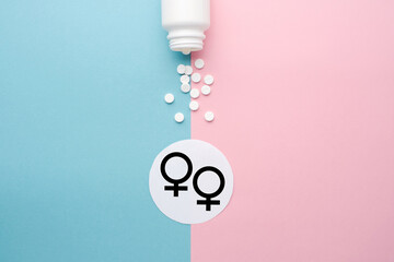 Pills scattered from a jar on a blue and pink background. Symbol of male and female. The concept of reproductive health and hormone therapy. Top view, background, space for text, copy space