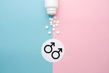 Pills scattered from a jar on a blue and pink background. Symbol of male and female. The concept of...