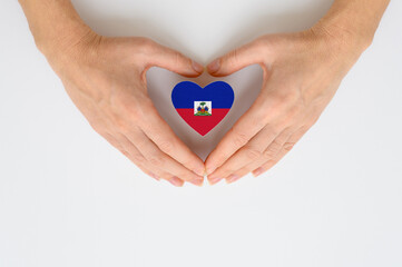 Flag of Haiti in the shape of a heart in female hands. The concept of providing humanitarian...