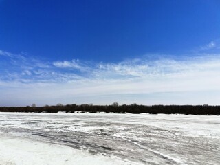 landscape with snowy river and blue sky in winter