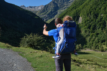 father with baby carrier backpack hiking in the mountains. father and daughter , family adventure, outdoor vacation, healthy life.