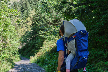 father with baby carrier backpack hiking in the mountains. father and daughter , family adventure, outdoor vacation, healthy life.