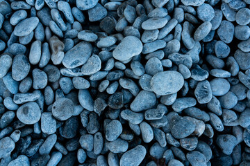 Black stones or rocks with a smooth rounded surface. Close up of pebbles on the sea shore.