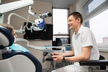 Fototapeta premium Dentist communicates with patient in dental office using digital tablet