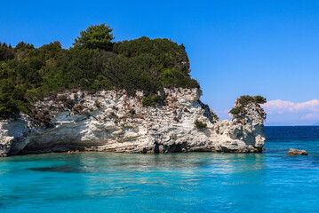 Fototapeta premium Rocky Stone in Turquoise Water with Blue Sky in Greece. Summer Day in Antipaxos with Ionian Sea.