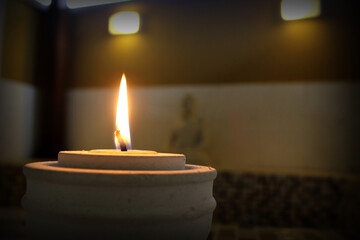 Candle reaching the end of its life with lots of wax dripping down the sides and pooled at the bottom