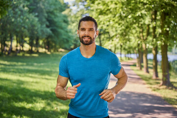 Smiling man with earphones running in the park