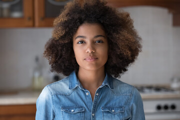 Pretty beautiful African American teen girl with Afro hairstyle looking at camera, posing for shooting at home. Black teenage high school student, teenage schoolgirl head shot portrait