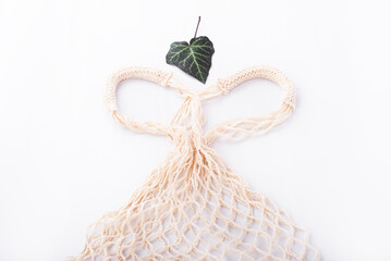 Fototapeta premium Eco friendly string bag and green leaf on white background, responsible consumption. zero waste concept.