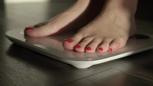 Young woman stands on a white electronic scale. The girl controls, loses weight.