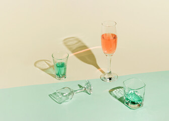 Creative concept with a glass of champagne and drink. Minimal idea of an event on pastel beige and green background.