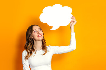 young woman looks at a round blank speech bubble isolated on an orange background. Student holding...