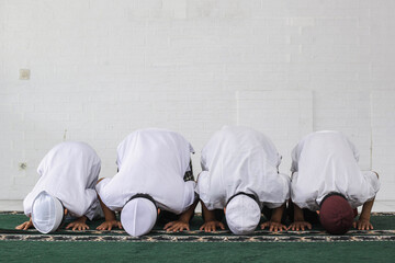 A group of Muslims are praying with prostrating movements in the mosque