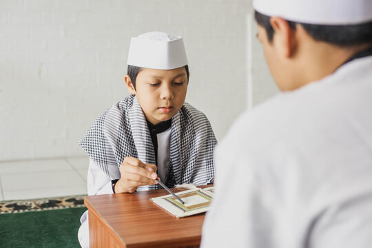 Portrait of a religious Muslim child learning to read the Koran in arabic style clothes in the mosque