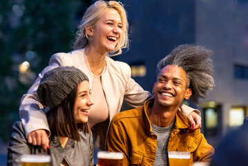 young blonde woman smiling and embracing her friends, multiracial people having fun at beer pub, social gathering and youth culture