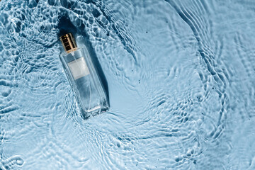 Perfume bottle on blue water wavy background. Fresh sea fragrance concept. Women's and men's...