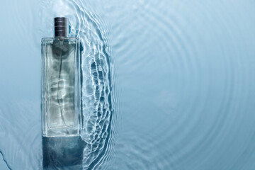 Perfume bottle on blue water wavy background. Fresh sea fragrance concept. Pure