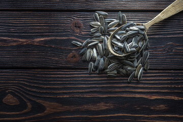 Sunflower seeds in a wooden spoon on a dark wooden background