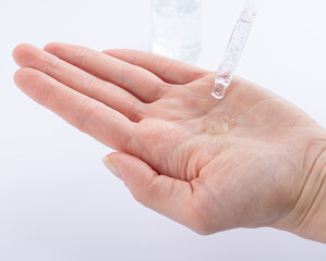 A woman's hand with a drop of serum or hyaluronic acid from a pipette. Close-up