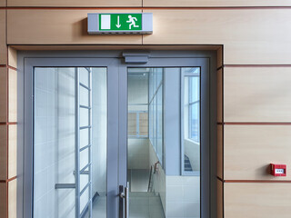 Emergency exit with glass door in airport office building. Emergency fire doors. Rescue signs icon...