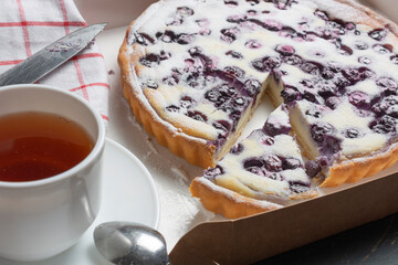 blueberry pie sprinkled with powdered sugar, a tea knife and a napkin. the concept of the holiday is a meeting of guests.