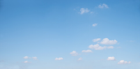 light blue sky background with some floatiing single cumulus clouds at the bottom half