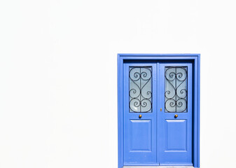Blue wooden door of traditional design on white wall, minimal architectural image.
