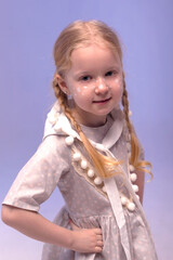 A little beautiful and sweet girl in a stylishly festive dress and with a dwarf hat in a white interior. Photo with selective focus and tinting.The child smiles and looks at the camera.