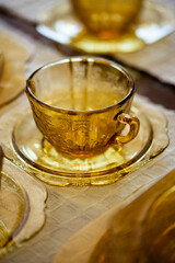 table setting with antique tea glass set with filigree pattern. yellow glass service in the interior. vintage cup close-up