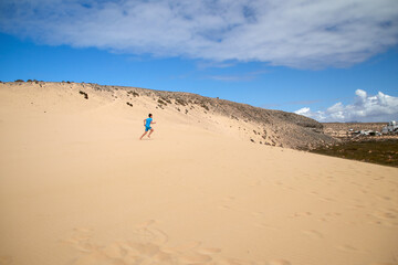 Fototapeta na wymiar a boy runs across the sand dunes