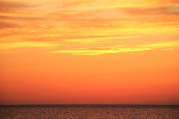 海の向こうに見える、オレンジ色の美しい夕焼けの空の写真素材