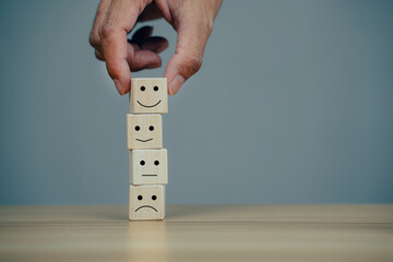 Satisfaction concept, Businessman choose smiley face a on wood cube.