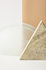 concrete tile in the shape of a triangle, beige corrugated cardboard and a glass arch on a light background