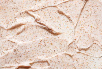 Irregular pattern of creamy organic scrub with brown grains professional skincare product as background close view from above