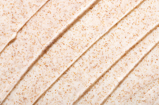 Smears of natural facial scrub with orange grains professional salon skincare product as background close view from above