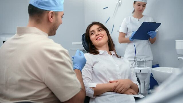 Dentistry male doctor and female smiling patient talking discussing tooth treatment at clinic