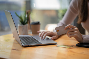 Close up woman shopping, paying by credit card, buying goods or ordering online, using a laptop, login internet bank service, typing on a keyboard