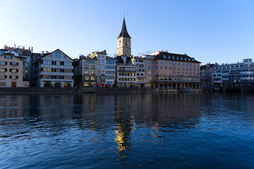 Fototapeta na wymiar Church tower of medieval protestant church St. Peter at the old town of Zürich with river Limmat in the foreground on a sunny winter day. Photo taken February 5th, 2022, Zurich, Switzerland.