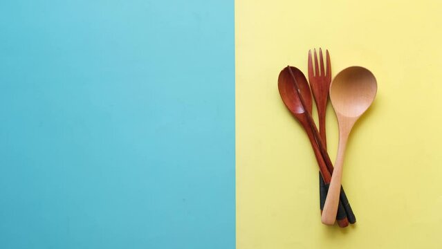 putting wooden cutlery forks on light yellow background 