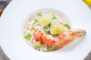 Plate of crab risotto served with a boiled crab claw, selective focus, close-up, horizontal shot