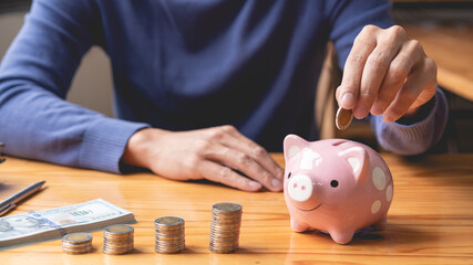 saving concept the male picking his coin to drop it into a pink piggy bank as his money saving up for this month © snowing12