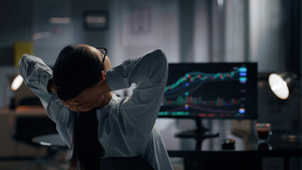 Rear view of successful broker relax on chair with hands behind her head. 