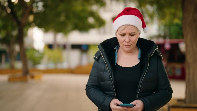 Mother and son holding christmas gift using smartphone at park