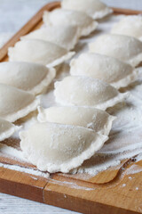 A raw homemade dumplings on wooden board.