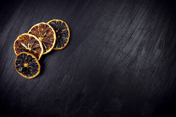 Four sliced mugs of dried lemons on black table