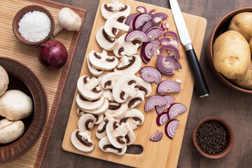 Sliced mushrooms champignon with red violet onion on wooden cutting board on kitchen. Top view, flat lay