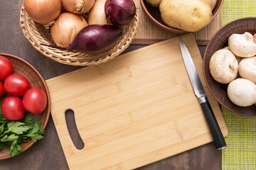 Wooden empty cutting board with copyspace. Mushrooms and vegetables for cooking vegetarian dish